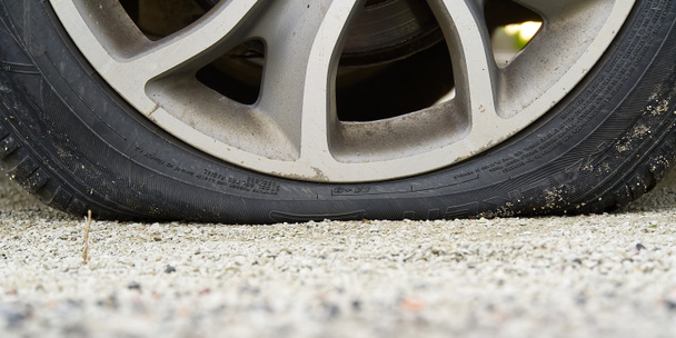Close-up of Flat rear tire on car. Damaged rear wheels on parking place. The right rear broken weel. - Photo, Image