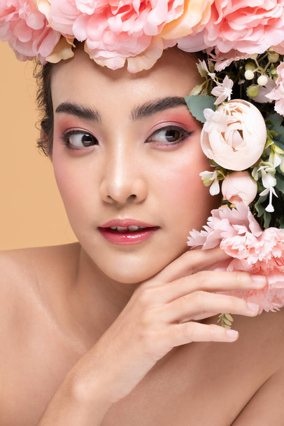 Beauty Asian young woman with big bouquet flowers on head smile with clean fresh skin Happiness and cheerful with positive emotional on Beige background,Beauty Cosmetics and Facial treatment Concept - Foto, afbeelding