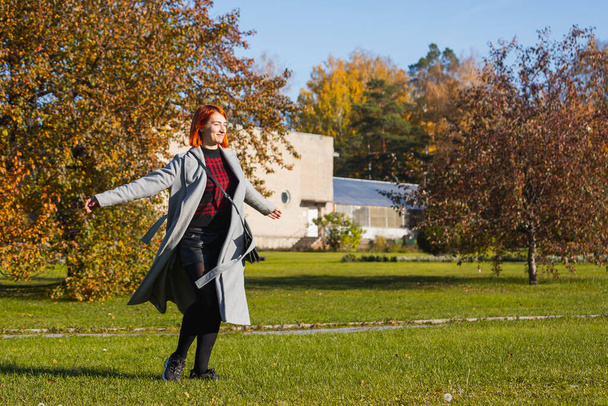 Fiatal nő meleg őszi ruhákban élvezi a meleg napot és örvénylik a városi parkban egy meleg őszi napon - Fotó, kép