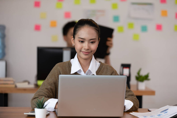 Happy Asian business woman in casual working with laptop and smile looking at camera at modern office or Co-Working Space,Business Startup Concept - Φωτογραφία, εικόνα