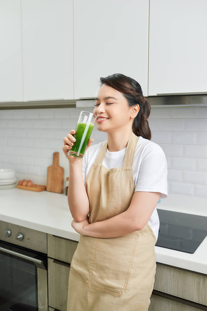 健康食品と食べる。緑のデトックス野菜スムージーを飲む幸せな若い女性.  - 写真・画像