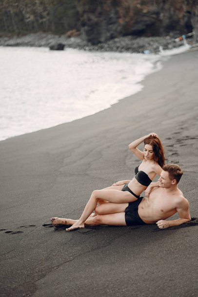 Elegant couple on a beach near rocks - 写真・画像