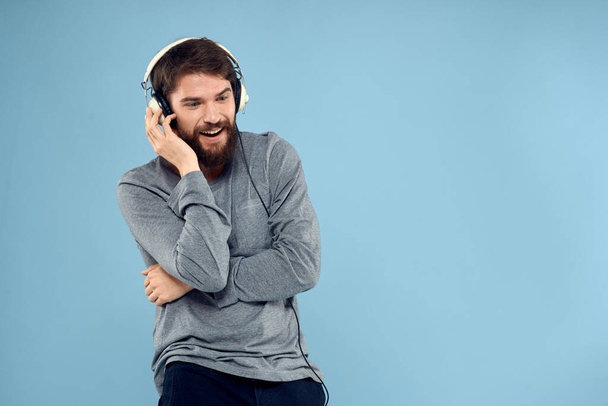 man met koptelefoon muziek emotie levensstijl moderne stijl technologie blauwe achtergrond - Foto, afbeelding