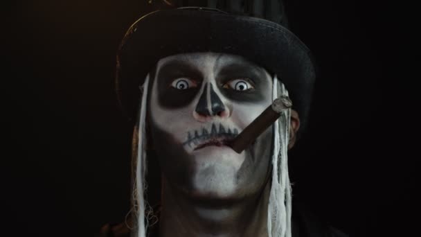 Hombre siniestro con horrible esqueleto de Halloween maquillaje fumar cigarro, haciendo caras, sonriendo, riendo - Metraje, vídeo