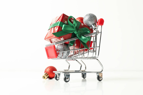 Einkaufswagen mit Weihnachtsschachtel und Zubehör auf weißem Hintergrund - Foto, Bild