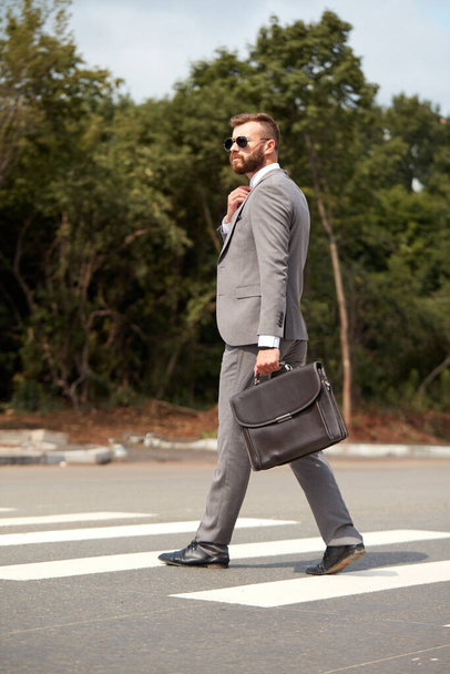 side view on caucasian businessman walking with bag - Foto, imagen