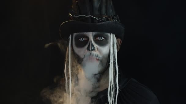 Gruseliger Mann in gruseligem Skelett-Halloween-Cosplay atmet Zigarettenrauch aus dem Mund - Filmmaterial, Video