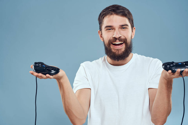 homme tenant manettes jeux mode de vie technologie console émotions blanc t-shirt fond bleu - Photo, image