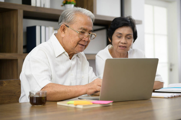 Onnellinen vanhempi aasialainen pari viettää aikaa surffata internetissä ja puhua perheen kanssa webbikamera, eläkkeelle käsite. - Valokuva, kuva