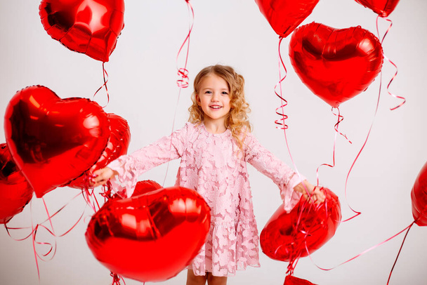 ξανθό κοριτσάκι με ροζ φόρεμα με κόκκινα μπαλόνια  - Φωτογραφία, εικόνα