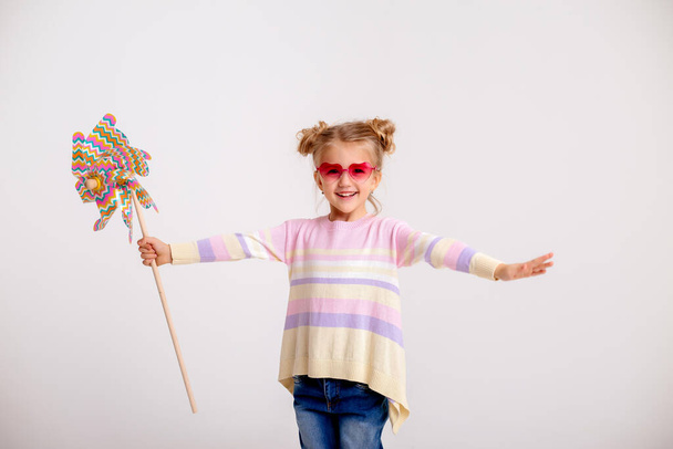 мила маленька дівчинка з іграшкою вітряної млини
 - Фото, зображення