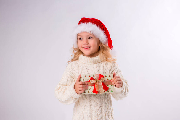 klein meisje in witte trui met cadeau, Kerst concept  - Foto, afbeelding