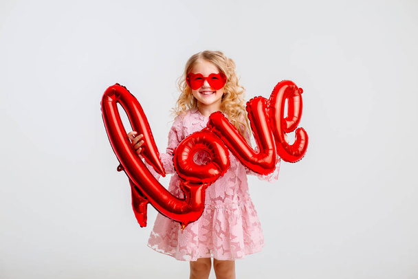 blond little girl in pink dress with red balloons  - Photo, Image