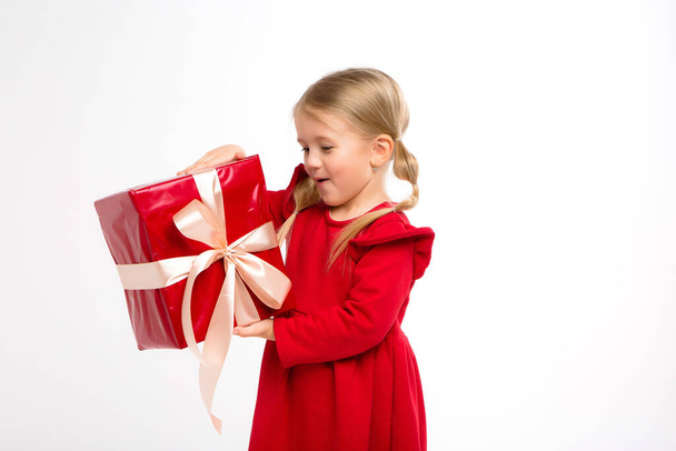 kleines Mädchen in rotem Kleid mit Geschenk, isoliert auf weiß  - Foto, Bild