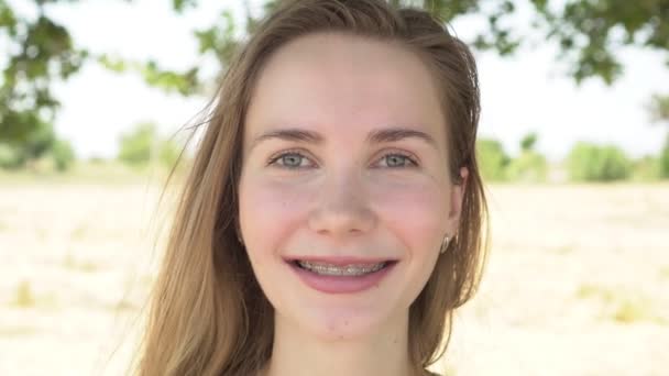Muotokuva nuoresta naisesta, jolla on hammasraudat. Nainen, jolla on hammasraudat hymyilevä - Materiaali, video