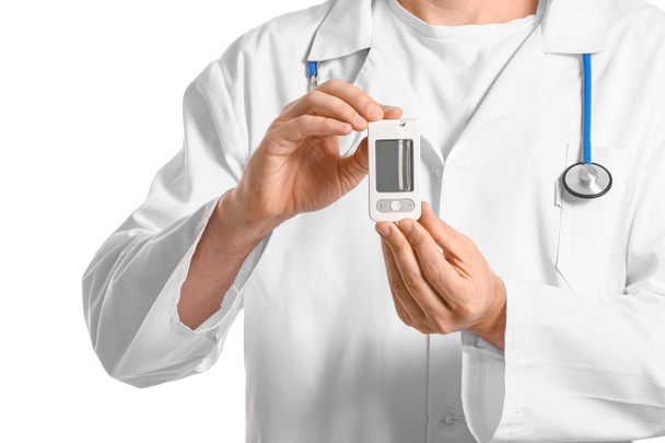 Doctor with digital glucometer on white background. Diabetes concept - 写真・画像