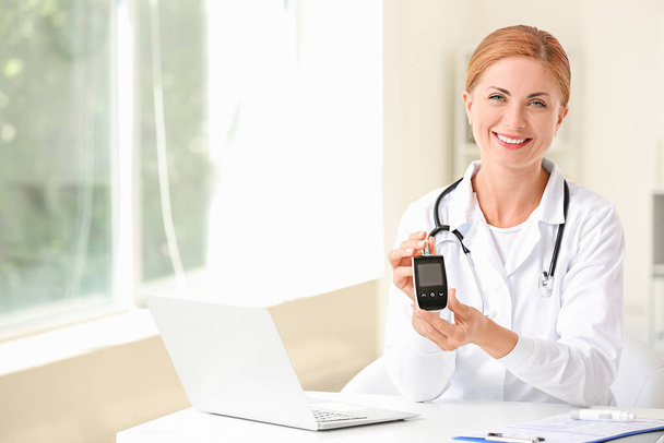 Doctor with digital glucometer in clinic. Diabetes awareness concept - Фото, зображення