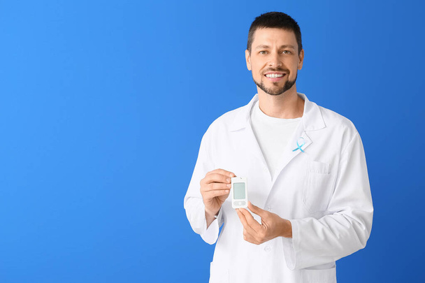 Doctor with digital glucometer on color background. Diabetes concept - Фото, изображение