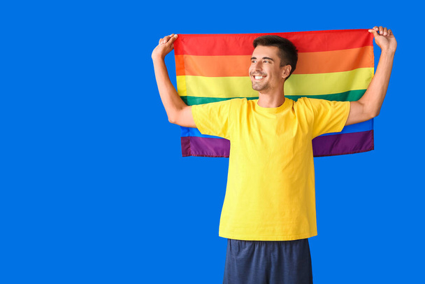Junger Mann mit LGBT-Flagge auf farbigem Hintergrund - Foto, Bild