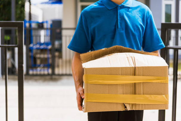 Asian young delivery man in blue uniform he emotional falling courier hold damaged cardboard box is broken at door front home, Accident bad transport shipment or poor quality delivery service concept - Photo, Image