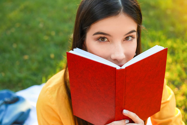 Gyönyörű fiatal nő olvas könyvet a parkban - Fotó, kép