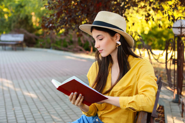 Beautiful young woman reading book in park - Foto, imagen