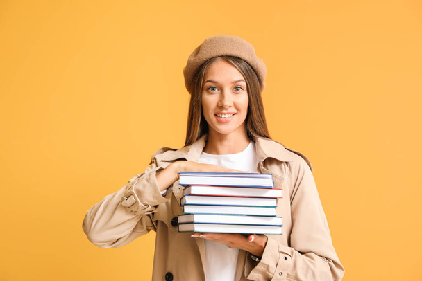Beautiful young woman with books on color background - Foto, afbeelding
