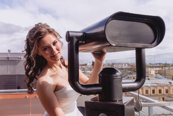 Portrait bride on observation deck stand on roof with panoramic view of old town. Pretty woman in wedding dresses on Sunny wedding day. Female in amazing view. Happy bride on background of city - Фото, зображення