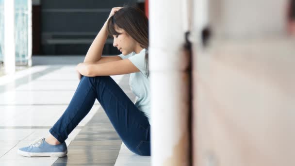 Triste adolescente asiática sentada en el pasillo de la escuela pensando en sus problemas. Movimiento lento - Imágenes, Vídeo