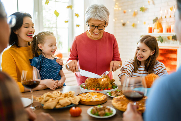 Happy Thanksgiving Day! Autumn feast. Family sitting at the table and celebrating holiday. Grandparents, mother, father and children. Traditional dinner. - Φωτογραφία, εικόνα