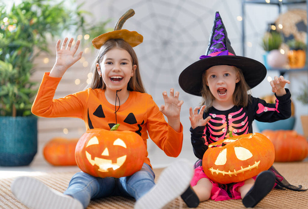 Cute little children girls with carving pumpkin. Happy family preparing for Halloween. Funny kids at home.    - Photo, image