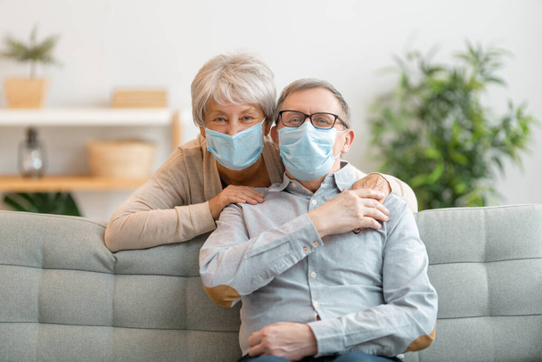 Senior couple wearing facemasks during coronavirus and flu outbreak. Virus and illness protection, home quarantine. COVID-2019. Taking on or taking off masks. - Zdjęcie, obraz