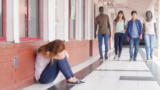 Triste adolescente asiatico seduto nel corridoio della scuola pensando ai suoi problemi. Gruppo di adolescenti in arrivo sulla sua strada - Filmati, video