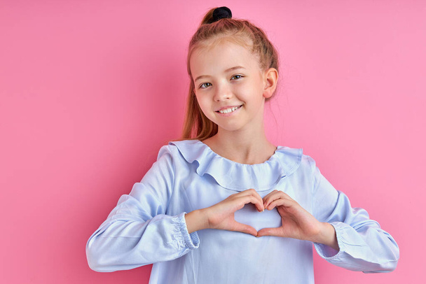 χαρούμενο καυκάσιο κορίτσι δείχνει καρδιά φτιαγμένη από τα χέρια της κάμερας - Φωτογραφία, εικόνα
