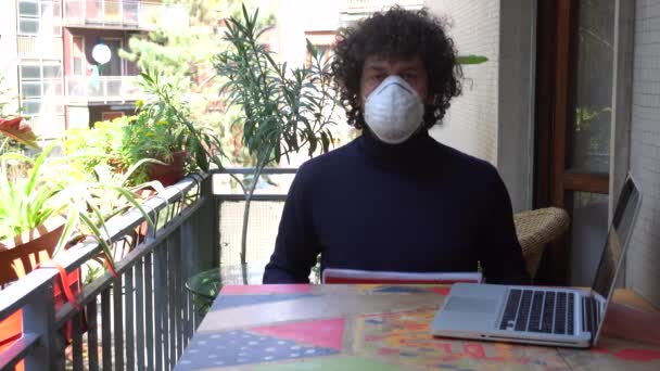 ヨーロッパ、イタリア、ミラノ-男性40歳自宅で自宅でn-cov19コロナウイルスの流行の検疫中にマスクをつけて-自宅で働いており、スペインアメリカの旗が感染していることを示しています - 映像、動画