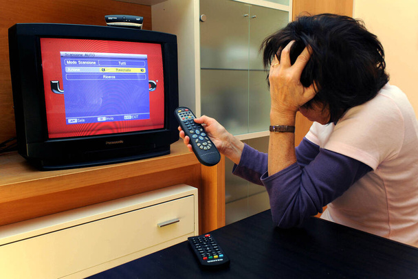 літня жінка намагається налаштувати телевізор
  - Фото, зображення