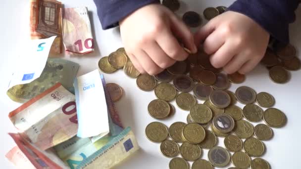 Billetes y monedas en euros en efectivo sobre una mesa blanca - Imágenes, Vídeo