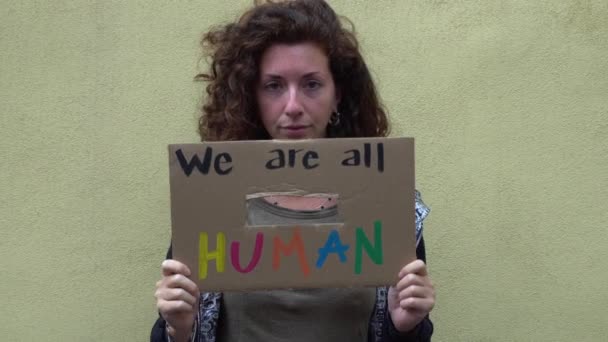 Amerika, USA - weißes lateinisches Mädchen mit Schild "Wir sind alle Menschen" protestiert und manifestiert. Konzept von Rassismus und sozialer Gewalt   - Filmmaterial, Video