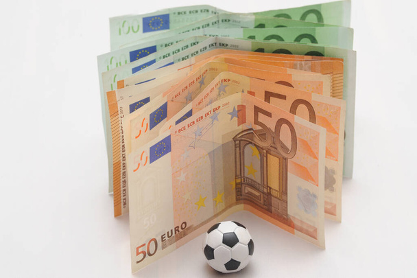 Jalkapalloa ja euroja. Vedonlyönti - vedonlyönti ja peliriippuvuus - urheilu ja jalkapallo - Valokuva, kuva