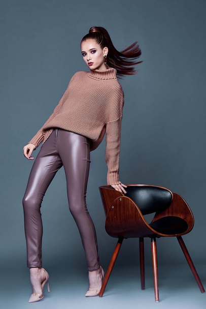 Beautiful woman sexy perfect body shape pretty face makeup wear beige wool cashmere sweater and skinny lather pants shoes accessory casual clothes for party brunette hair fashion model pose style. - Foto, Imagen