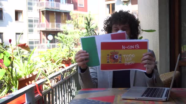 Europa, Italië, Milaan - Man 40 jaar oud thuis met masker tijdens n-cov19 Coronavirus epidemie quarantaine thuis - thuis werken en toont de vlag van Spanje en Italië besmet - Video