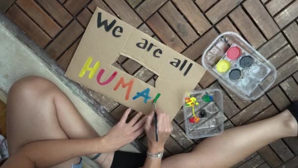 America, USA - La ragazza latina bianca che tiene il cartello "Siamo tutti umani" protesta e manifesta. Concetto di razzismo e violenza sociale   - Filmati, video