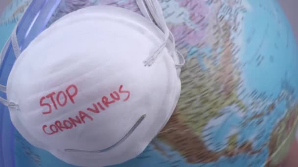 bílá maska s stop koronavirus znamení na pozadí zeměkoule  - Záběry, video