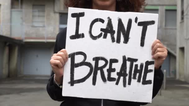 America, USA - La ragazza latina bianca che tiene il cartello "Non riesco a respirare" protesta e manifesta. Concetto di razzismo e violenza sociale   - Filmati, video