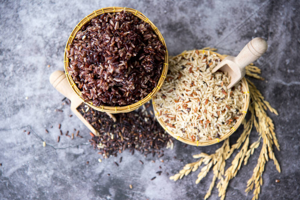 Ρύζι γιασεμί, Καφέ ρύζι σε ψάθινο καλάθι με ξύλινη κουτάλα, κίτρινο ρύζι paddy, χονδρό σιτάρι και χοντρό σιτάρι αγρότη βιολογικό μαύρο ρύζι, Επιλεκτική εστίαση. - Φωτογραφία, εικόνα