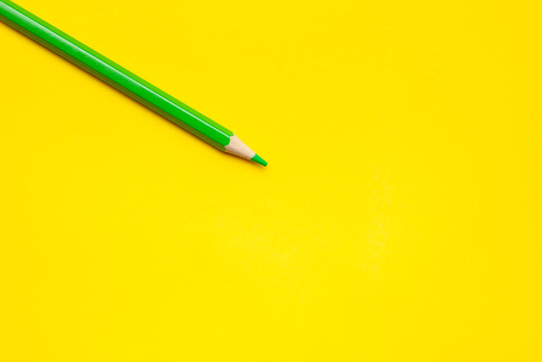 diagonal green sharp wooden pencil on a bright yellow background, isolated, copy space, mock up - Fotoğraf, Görsel