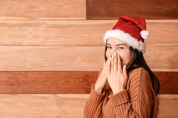 gelukkig jong vrouw in kerstman hoed op houten achtergrond - Foto, afbeelding