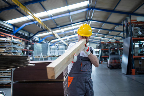 Marangoz üretim hattı işçisi fabrikadaki mobilya üretimi için ahşap malzemeyi kontrol ediyor.. - Fotoğraf, Görsel