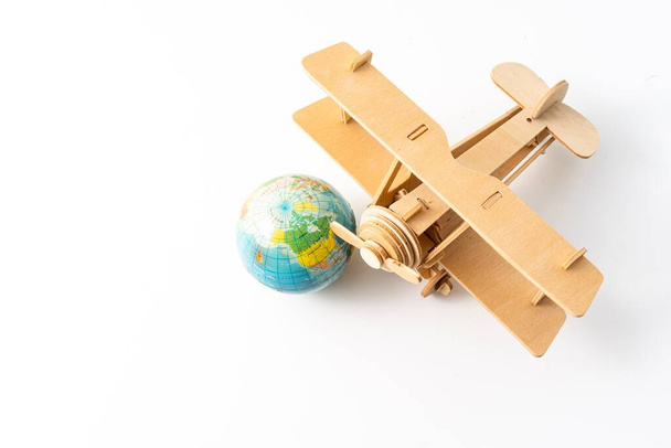 Miniatuur houten vliegtuig met een mini wereldbol. Reisconcept - Foto, afbeelding
