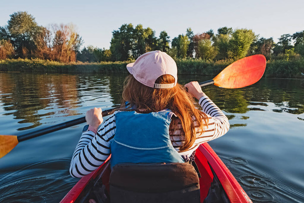 Woman paddling the kayak on river or lake - Foto, afbeelding